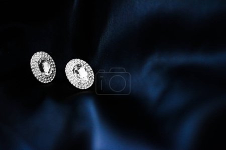 Foto de Pendientes de diamantes de lujo sobre fondo de seda azul oscuro, - Imagen libre de derechos