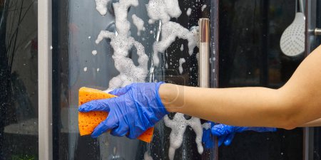 Foto de Limpieza de cabinas de vapor de ducha de depósitos de calcio. Limpieza en el baño. mano en guantes con trapo y detergente lavado ducha y vidrio - Imagen libre de derechos