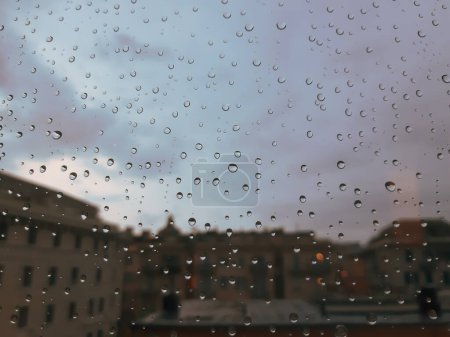 Téléchargez les photos : Goutte de pluie sur verre avec ville floue derrière - en image libre de droit
