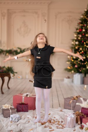 Téléchargez les photos : Une petite fille lance des confettis. Magie de Noël. Moments joyeux d'une enfance heureuse - en image libre de droit