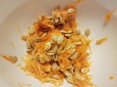Foto de Pumpkin seeds and orange pulp in container - Imagen libre de derechos