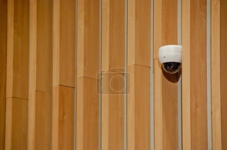 Foto de Cúpula de cámara de seguridad CCTV blanca moderna conectada a pared de madera - Imagen libre de derechos