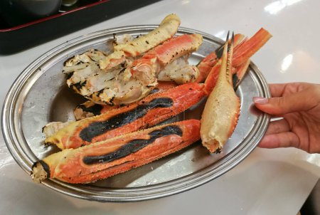 Foto de "Giant Alaska King Snow crab legs grilled on silver plate" - Imagen libre de derechos
