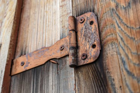 Téléchargez les photos : Charnière de porte vieille et rouillée tenant une porte en bois fermée - en image libre de droit