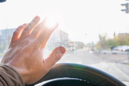 Foto de La mano del conductor al volante del coche cubre el sol cegador - Imagen libre de derechos