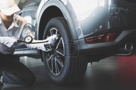 Foto de Inspección del hombre asiático Medida cantidad Neumáticos de goma inflados coche - Imagen libre de derechos