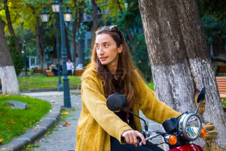 Photo for Smiling young woman on the scooter in the park - Royalty Free Image