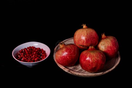 Photo for Pomegranates in wooden plate and seeds in white bowl - Royalty Free Image