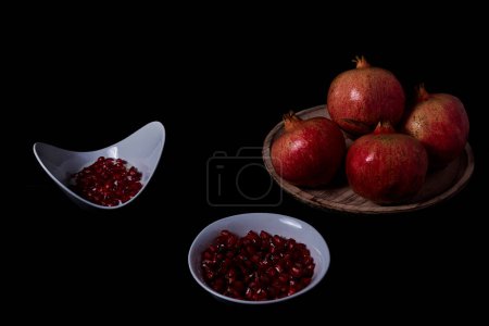 Photo for Pomegranates in wooden plate and seeds in bowl with yogurt - Royalty Free Image