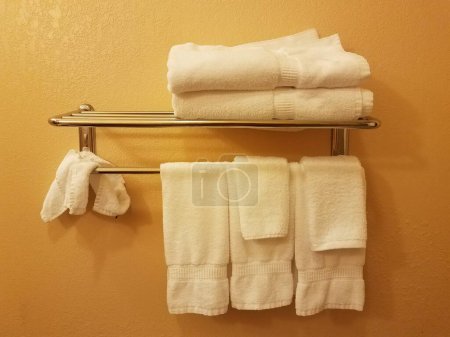 Téléchargez les photos : Mur jaune ou orange avec des serviettes blanches suspendues sur le rack dans la salle de bain - en image libre de droit