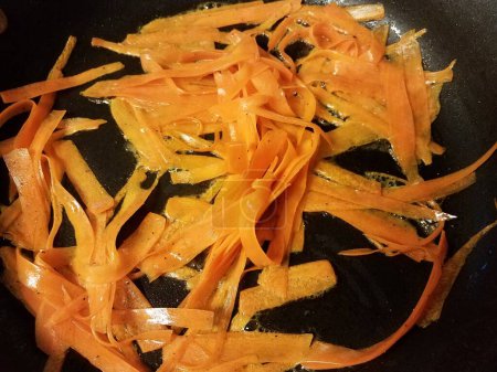 Photo for Orange carrot stripes in oil in frying pan - Royalty Free Image