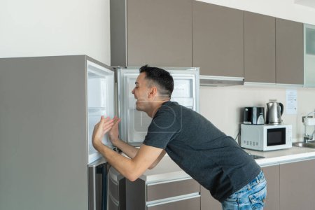 Photo for On a hot day, the guy cools with his head in the refrigerator. Broken air conditioner - Royalty Free Image