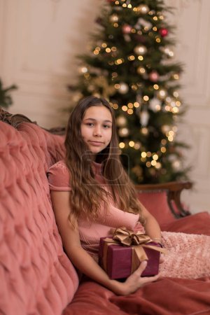 Téléchargez les photos : Fille avec un cadeau de Noël de vacances dans un intérieur élégant - en image libre de droit
