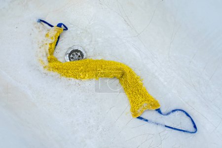 Photo for The washcloth lies in the bathtub in foam surrounded by water - Royalty Free Image