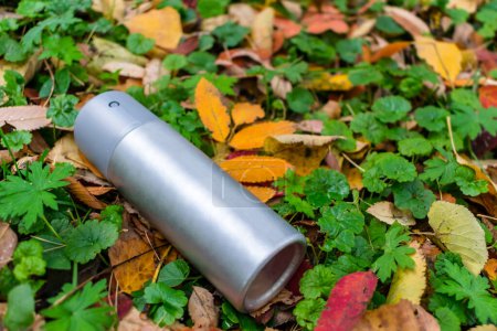 Photo for Trash in the form of an antiperspirant spray thrown on the lawn in the autumn foliage - Royalty Free Image