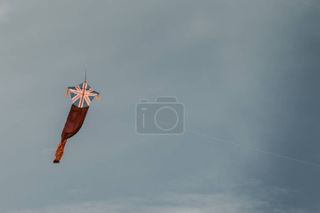 Téléchargez les photos : "Mouche cerf-volant contre le ciel sombre et lunatique, drapeau britannique" - en image libre de droit