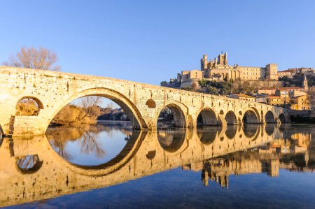 Foto de El viejo puente de Bziers su reflexión simétrica sobre el río Orbe en el Herault en Occitanie, Francia. - Imagen libre de derechos