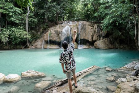 Photo for "Man standing on the stone at Erawan waterfall at National Park, " - Royalty Free Image