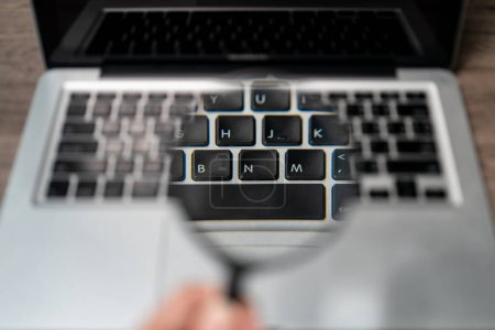 Téléchargez les photos : Ordinateur portable avec loupe sur le clavier d'ordinateur portable - en image libre de droit