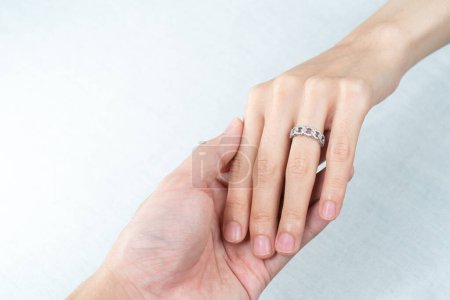 Téléchargez les photos : "Homme mettant bague en diamant sur la main de la femme sur fond blanc." - en image libre de droit