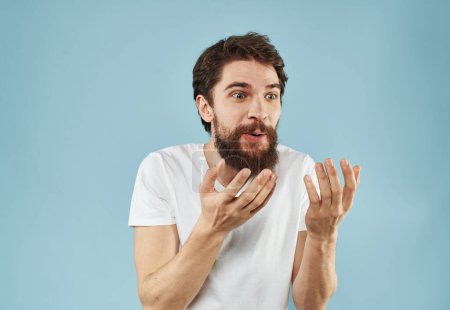 Téléchargez les photos : "Homme perplexe avec une barbe sur un fond bleu émotions de surprise" - en image libre de droit
