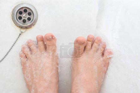 Téléchargez les photos : Peau ridée sur les orteils pendant la douche dans la salle de bain - en image libre de droit