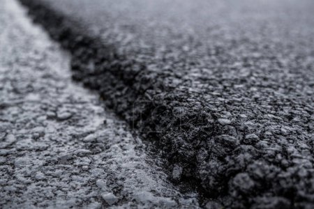 A large layer of fresh hot asphalt. Layer of asphalt raw material in a shallow depth of field. Rollers rollin fresh hot asphalt on the new road. Road construction. Construction of a new road.