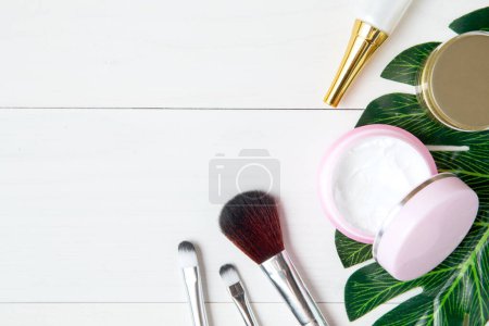 Téléchargez les photos : "produits cosmétiques et soins de la peau et feuilles vertes sur bois blanc ta
" - en image libre de droit
