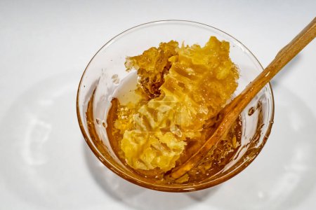 Téléchargez les photos : "miel nid d'abeille dans un bol en verre avec cuillère en bois" - en image libre de droit