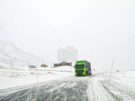 Téléchargez les photos : "Conduite à travers un paysage routier enneigé, Norvège. Camion vert devant." - en image libre de droit