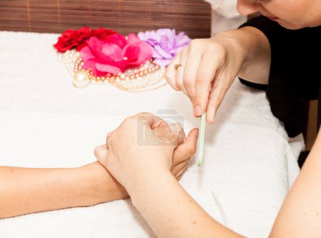 Photo for "The beautician polish the client's nails before putting nail pol" - Royalty Free Image