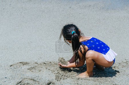 Téléchargez les photos : Petite fille jouer avec le sable - en image libre de droit