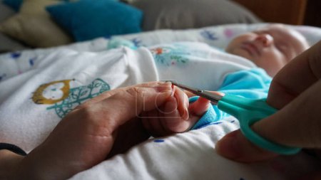 Téléchargez les photos : Les ongles d'un nouveau-né sont coupés avec des ciseaux - en image libre de droit