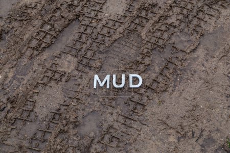 Foto de Palabra barro con letras de metal plateado sobre la superficie de tierra húmeda - Imagen libre de derechos