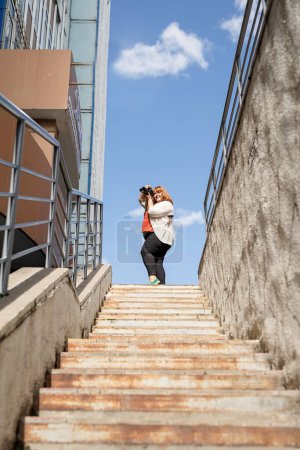 Foto de Más tamaño mujer fotógrafo al aire libre en la construcción de escaleras - Imagen libre de derechos