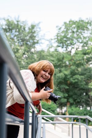 Photo for Plus size woman photographer outdoors holding a camera and laughing - Royalty Free Image