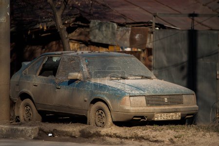 Foto de "TULA, RUSIA - 13 DE ABRIL DE 2012: automóvil sucio abandonado a un lado de la carretera de primavera con fondo de gueto de barrio pobre" - Imagen libre de derechos