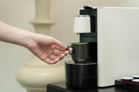 Photo for Coffee capsule machine maker. Hand takes a ceramic cup of coffee - Royalty Free Image