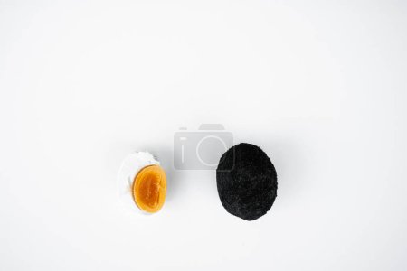 Photo for An old duck egg recipe in ash. Salty pickled duck egg in ash on a white background - Royalty Free Image