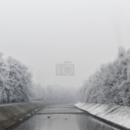 Téléchargez les photos : Hiver à Sarajevo. La rivière Miljacka à Sarajevo pendant l'hiver. En hiver, Sarajevo a le brouillard et la pollution avec peu de neige sur la côte. - en image libre de droit