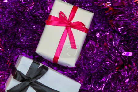 Téléchargez les photos : Cadeaux enveloppés avec du papier blanc sur tinsel violet - en image libre de droit