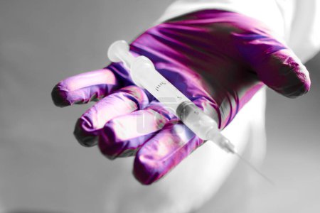 Photo for Hand in surgical glove holding a syringe - Royalty Free Image