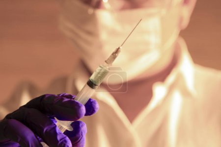 Téléchargez les photos : Assistant de laboratoire tenant une seringue contenant le virus covid-19 - en image libre de droit