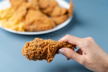 Photo for "Hand holding drumsticks, crispy fried chicken with french fries " - Royalty Free Image