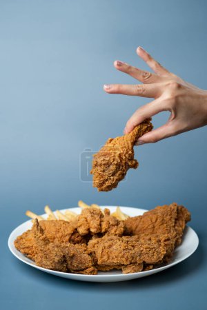 Photo for "Hand holding drumsticks, crispy fried chicken in white plate on " - Royalty Free Image
