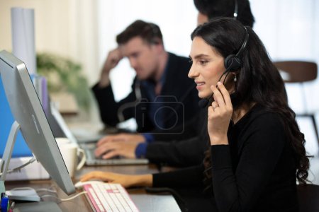 Téléchargez les photos : "side view.the opérateur de centre d'appels et ses collègues travaillent dans le bureau." - en image libre de droit