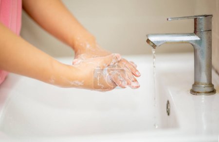 Foto de Lavando la mano con jabón de espuma en el lavabo del baño. - Imagen libre de derechos