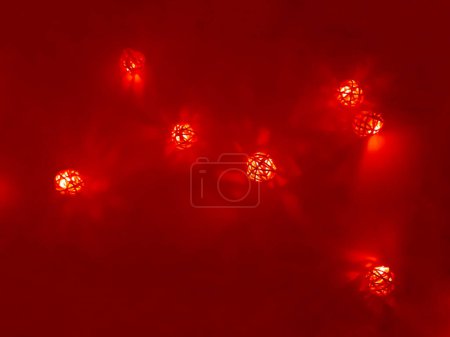 Photo for "Garland of small decorative luminous balls, red light, night time" - Royalty Free Image