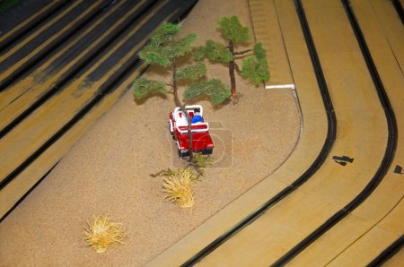 Foto de Pequeña casa de juguete, coche rojo, árboles y linterna en pista de juguete, macro - Imagen libre de derechos