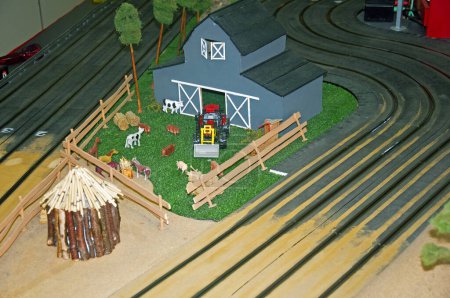 Téléchargez les photos : Petit parc de jouets gris, tracteur rouge et grange en bois - en image libre de droit